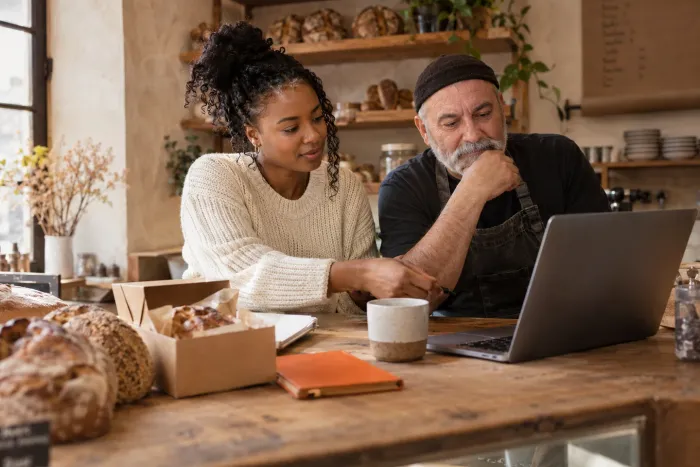 A baker and a freelancer working together on a laptop.