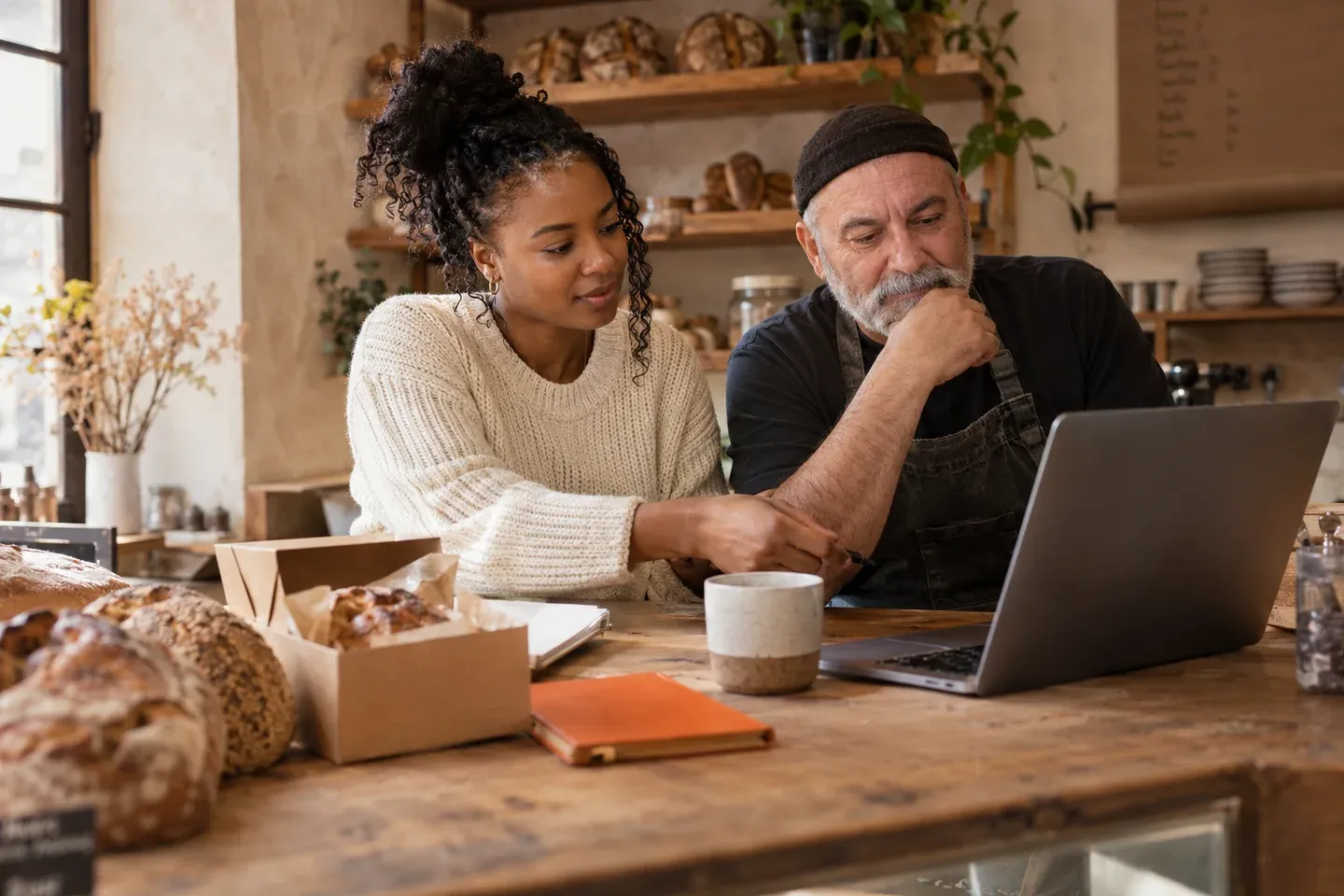 A freelancer and a local baker working together at a laptop.