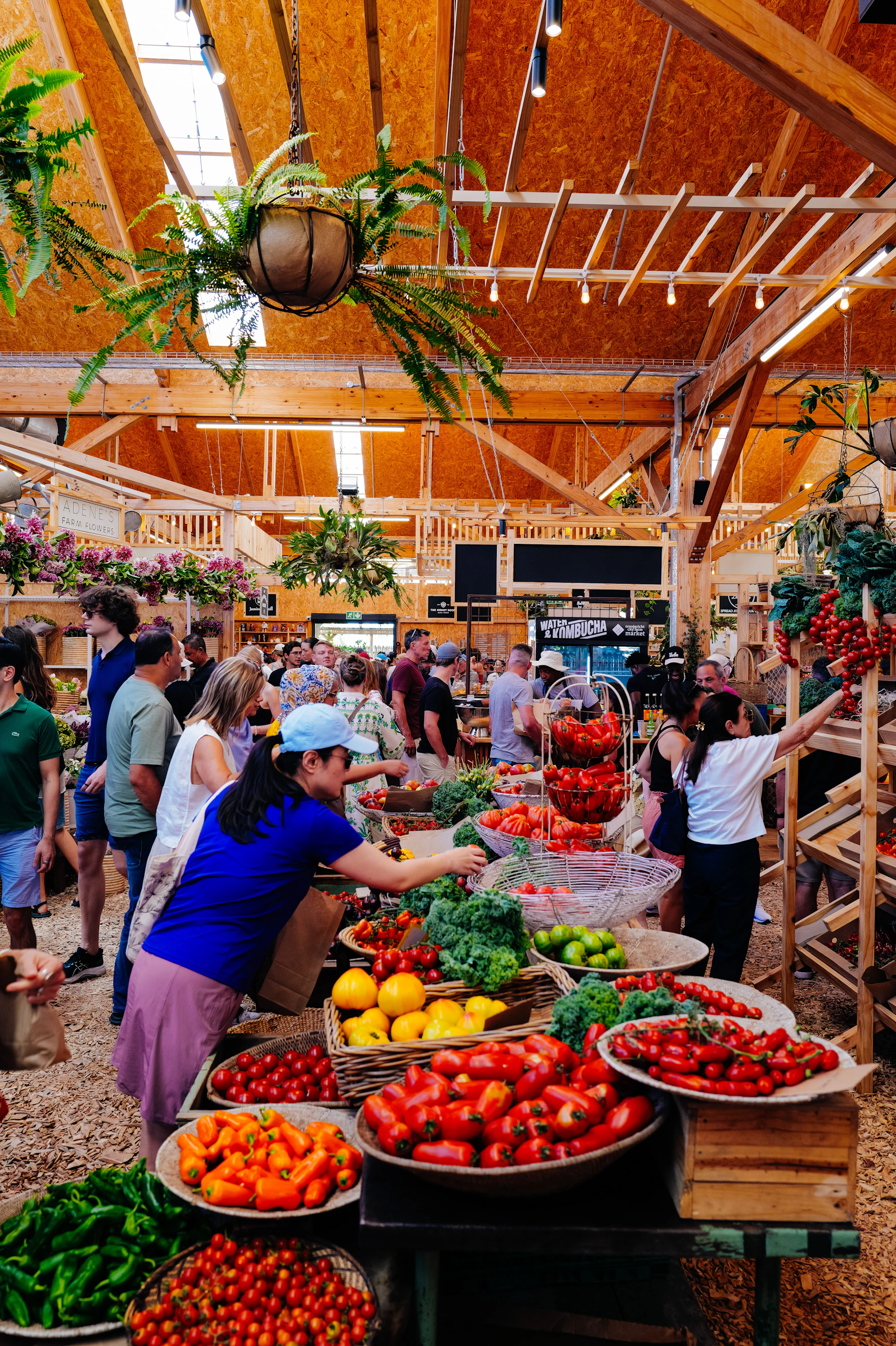 People shopping among fresh produce stalls in an indoor market.